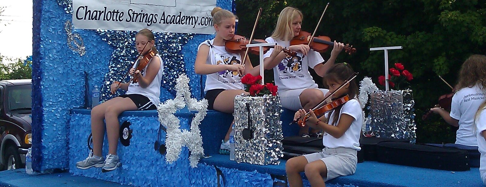 Charlotte Strings Academy students playing violin on a parade float